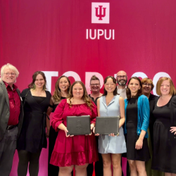 Group photograph of Herron School of Art and Design faculty and staff surrounding Ginger Miller and Michaela Di Palmo, two of the IUPUI Top 100 honorees