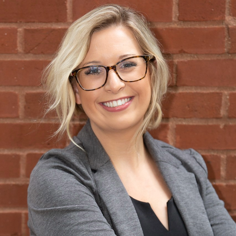 Headshot for Herron associate faculty member Bailee Chilman wearing glasses, a gray blazer, and a black dress top
