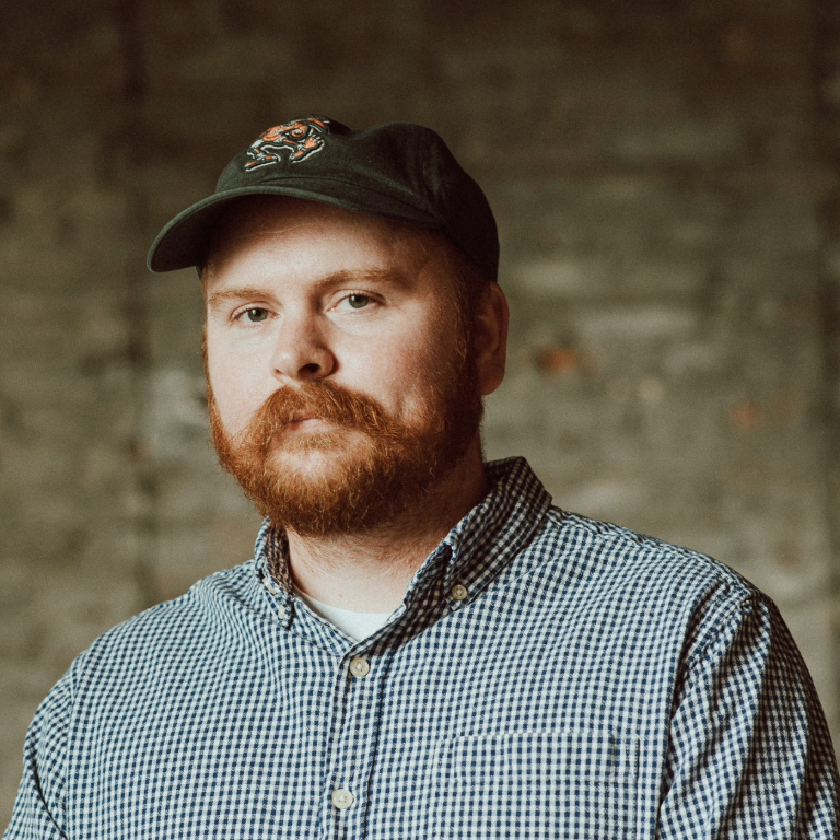 Headshot of Herron associate faculty member Joe Swanson in a checked shirt and baseball hat