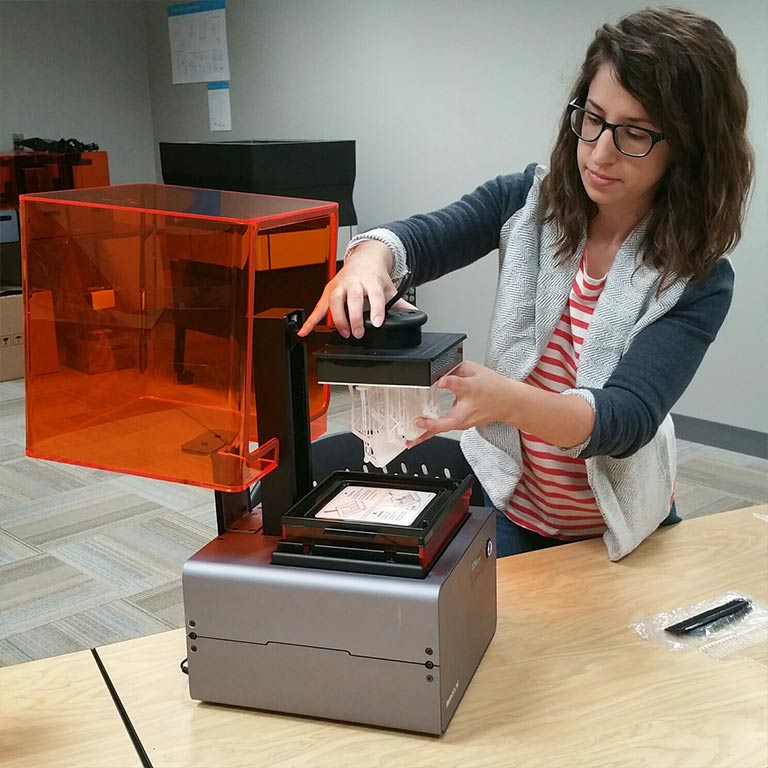 A female student creates a sculpture using a 3D printer in the Think It Make It Lab.