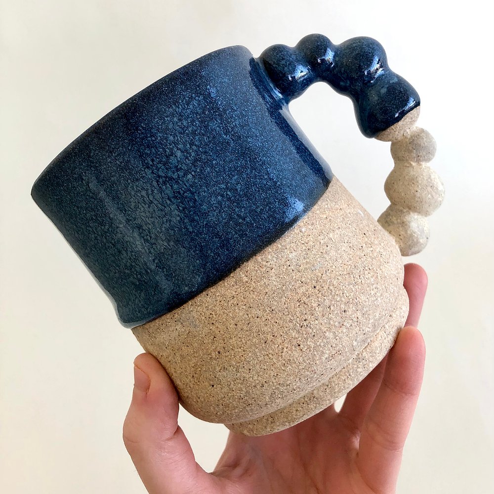 A blue and white glazed mug in someone's hand